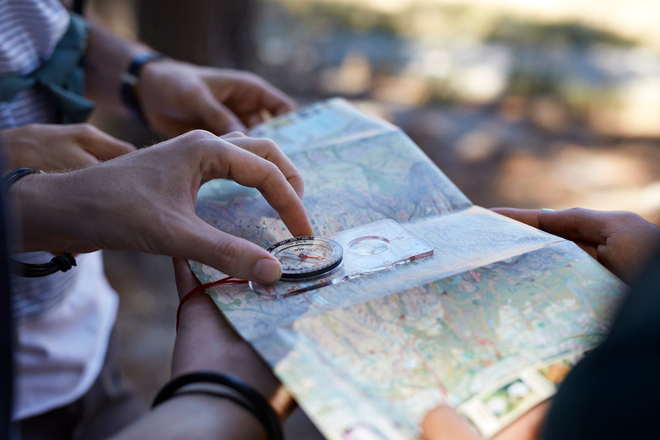 close up of hands holding compass up to map