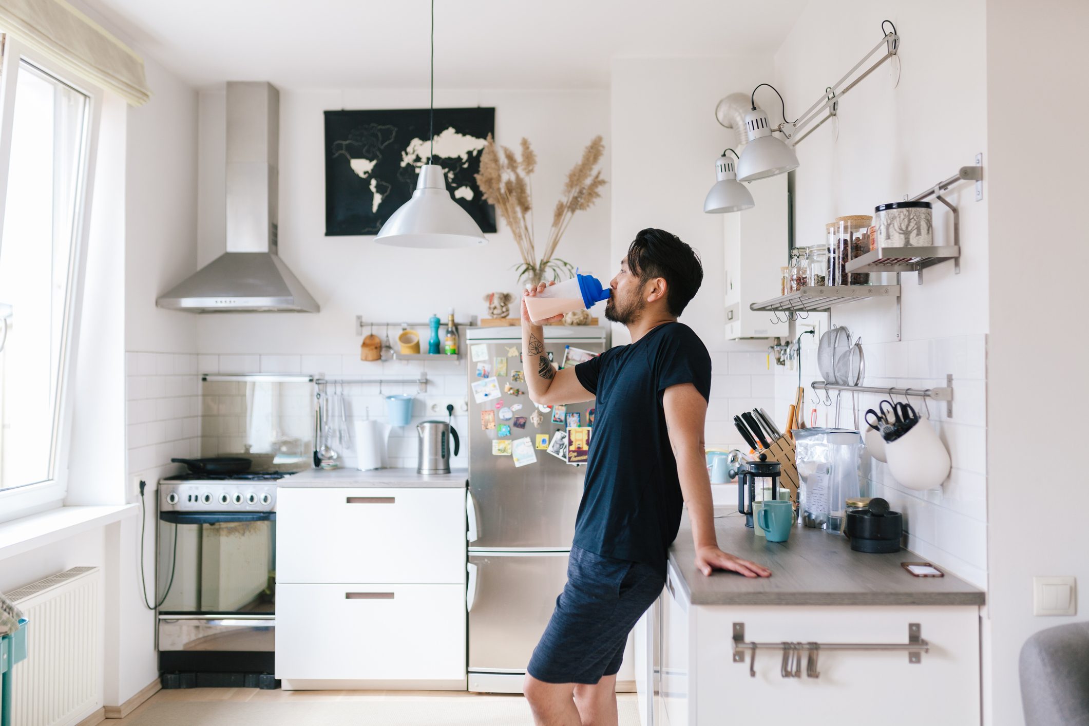 Asian man drinks protein shake after home workout