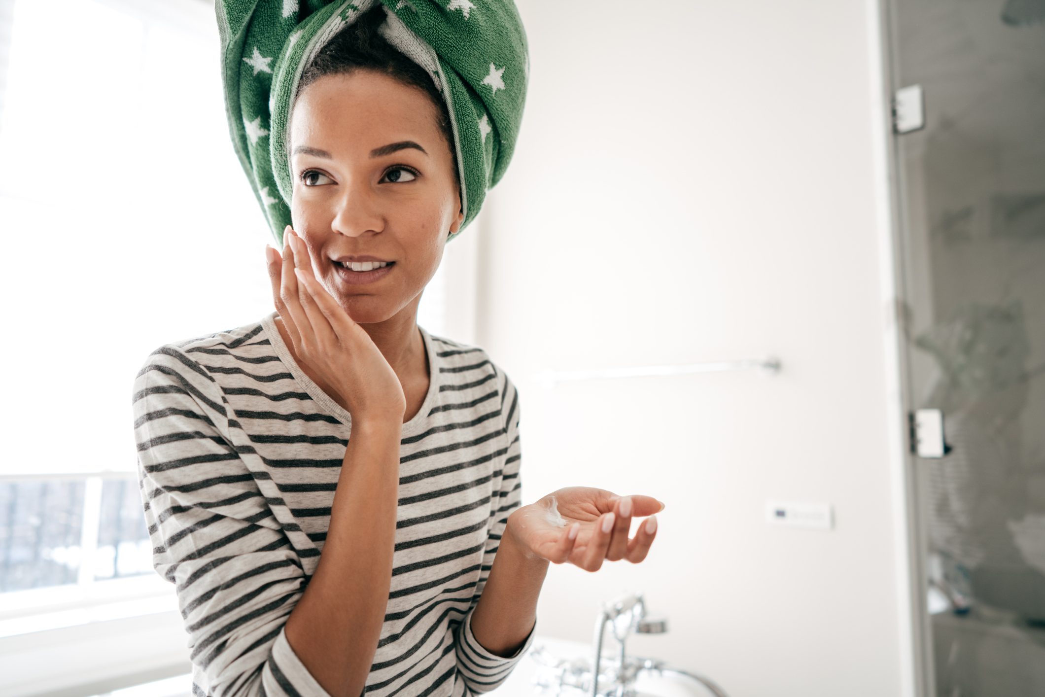Woman with towel applying face cream