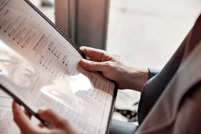 Cropped image of man holding menu while sitting in restaurant