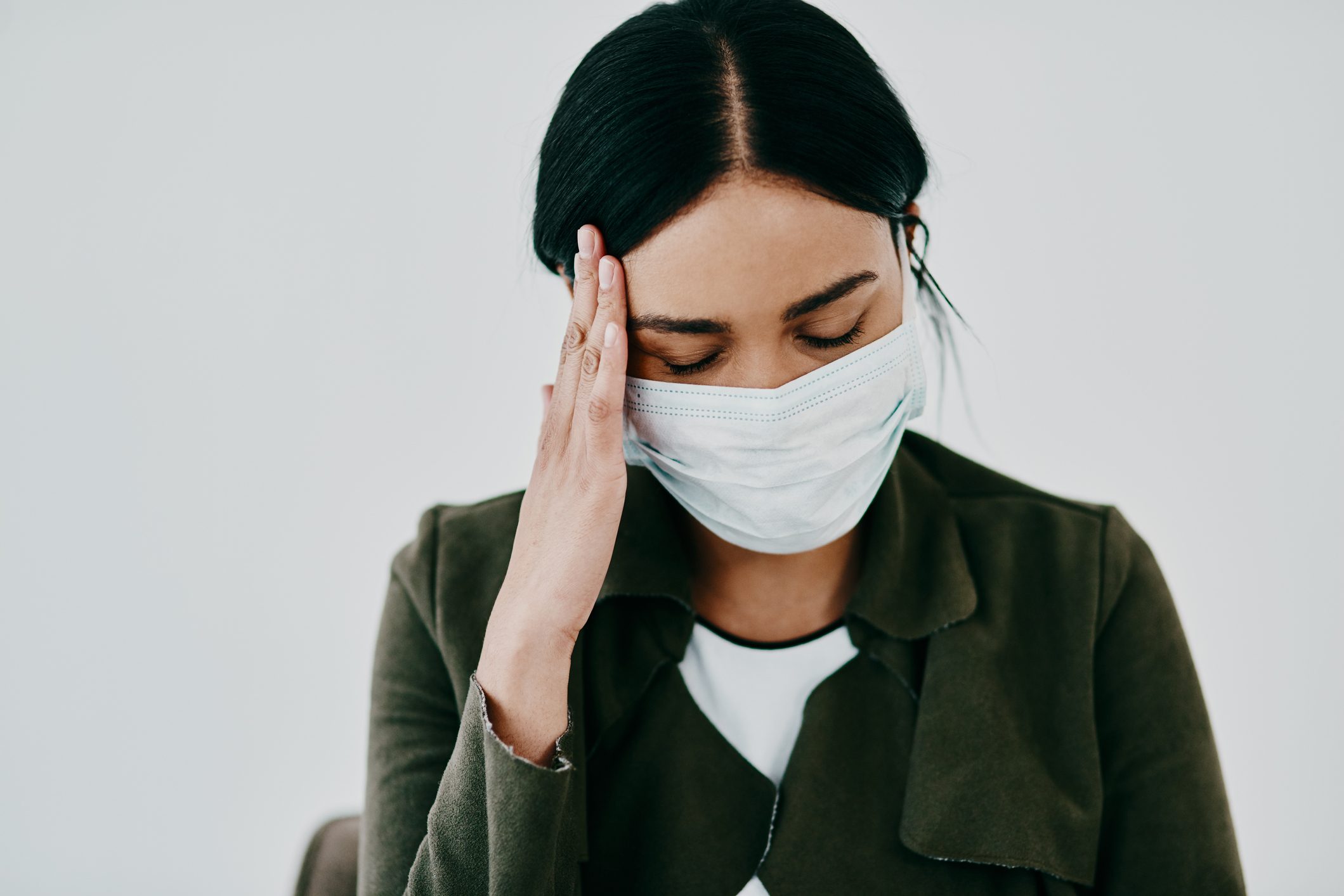 woman wearing a face covering and experiencing a headache