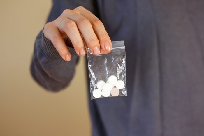 Treatment tablets. Close-up of a white pack pills in woman's fingers.