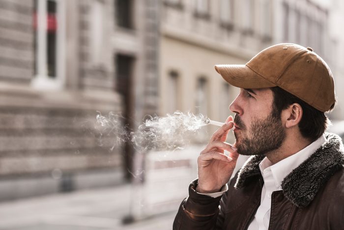 Portrait of young man with baseball cap smoking cigarette