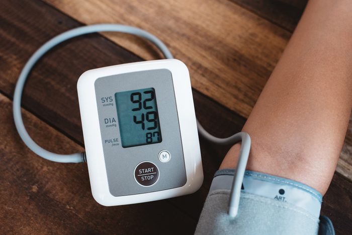 Cropped Hand Of Person With Blood Pressure Gauge On Wooden Table