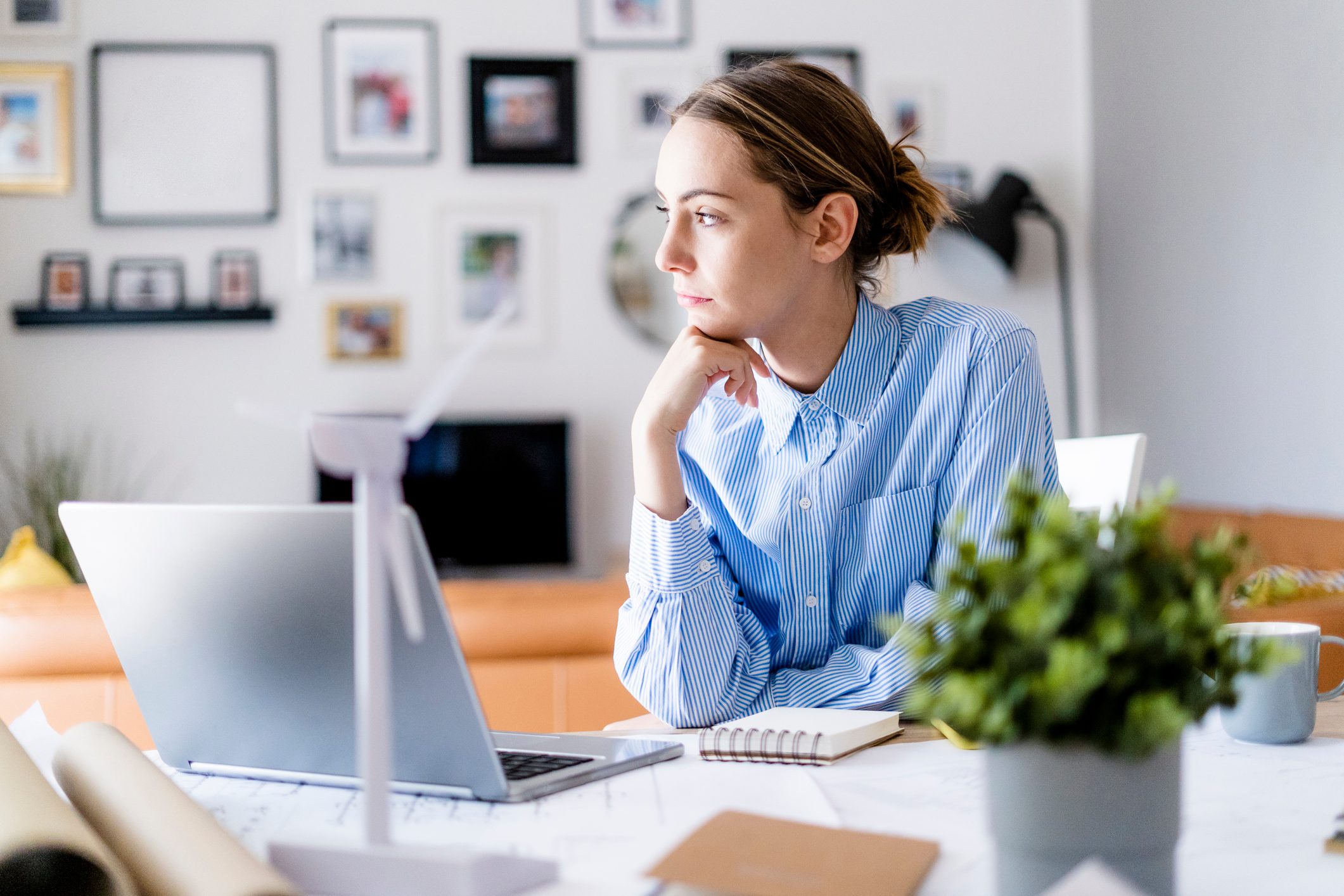 Woman in office looking sideways with wind turbine model on table