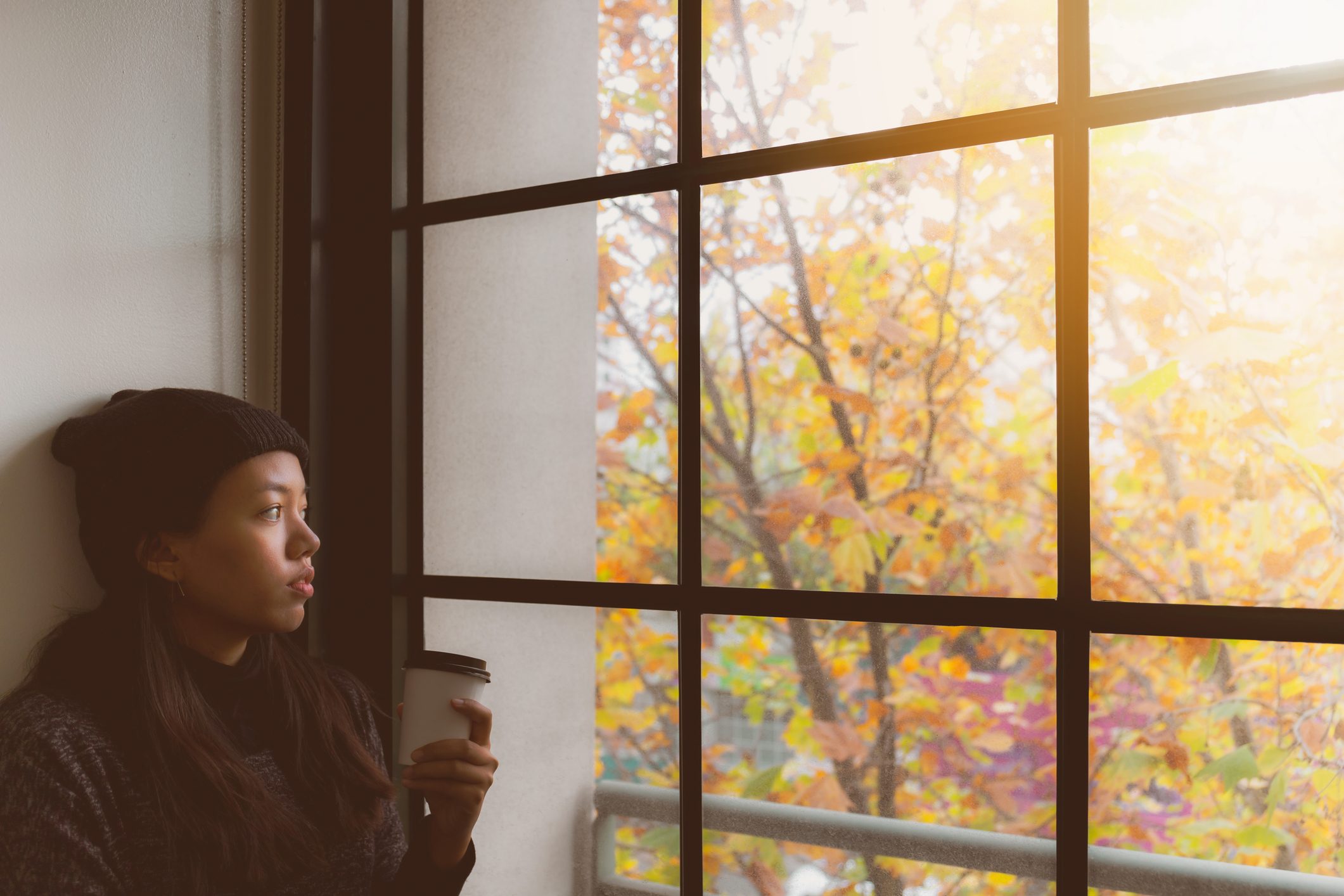 Woman Looking Through Window While Holding cup