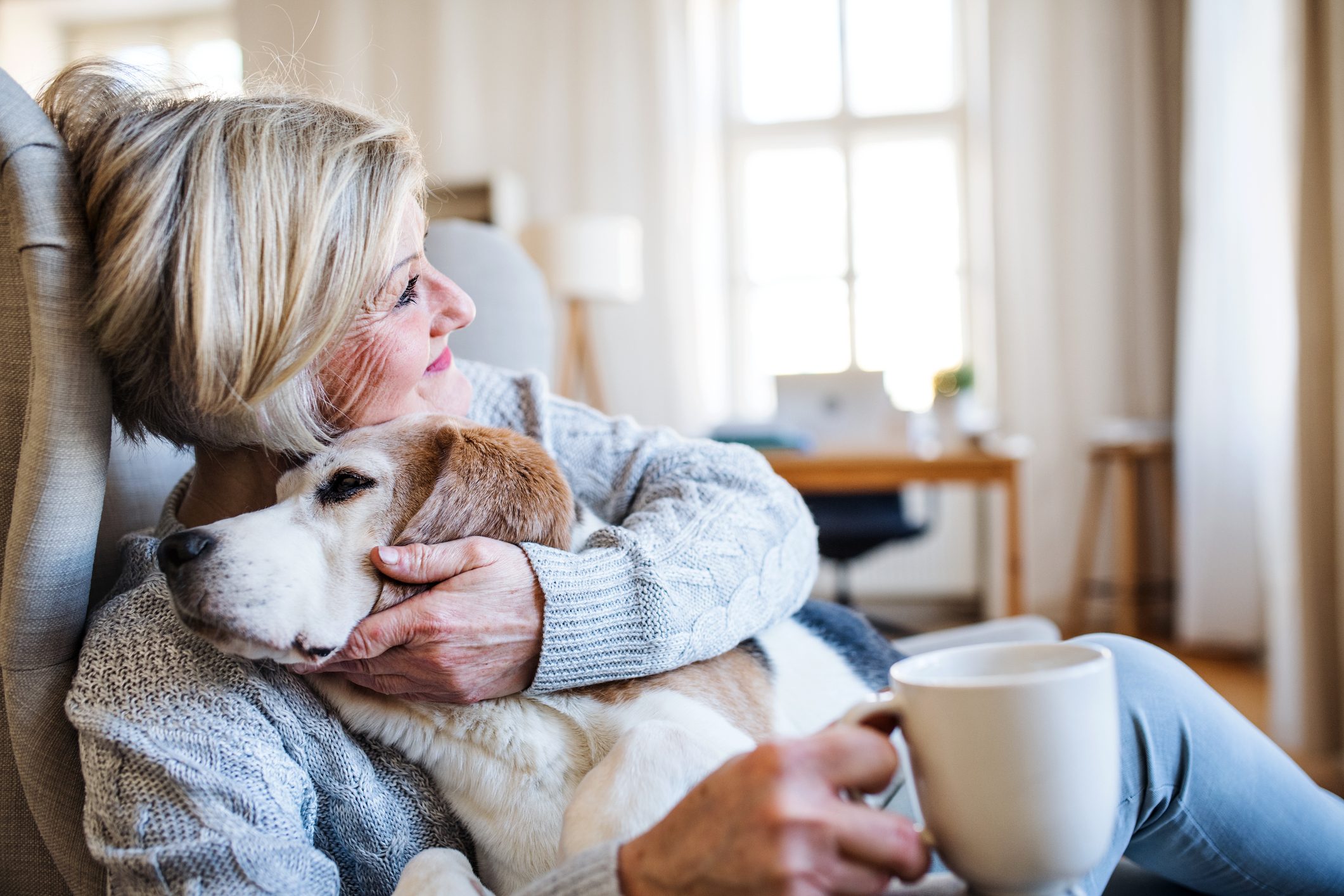 An active senior woman with a dog at home, resting.