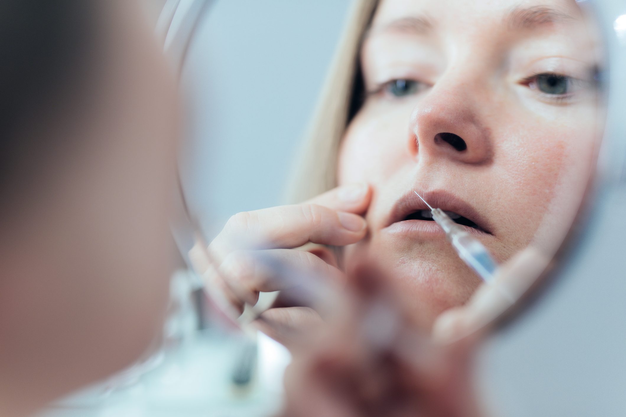 Woman doing botox injection in lips.
