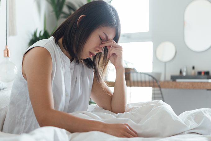 woman with headache sitting in bed