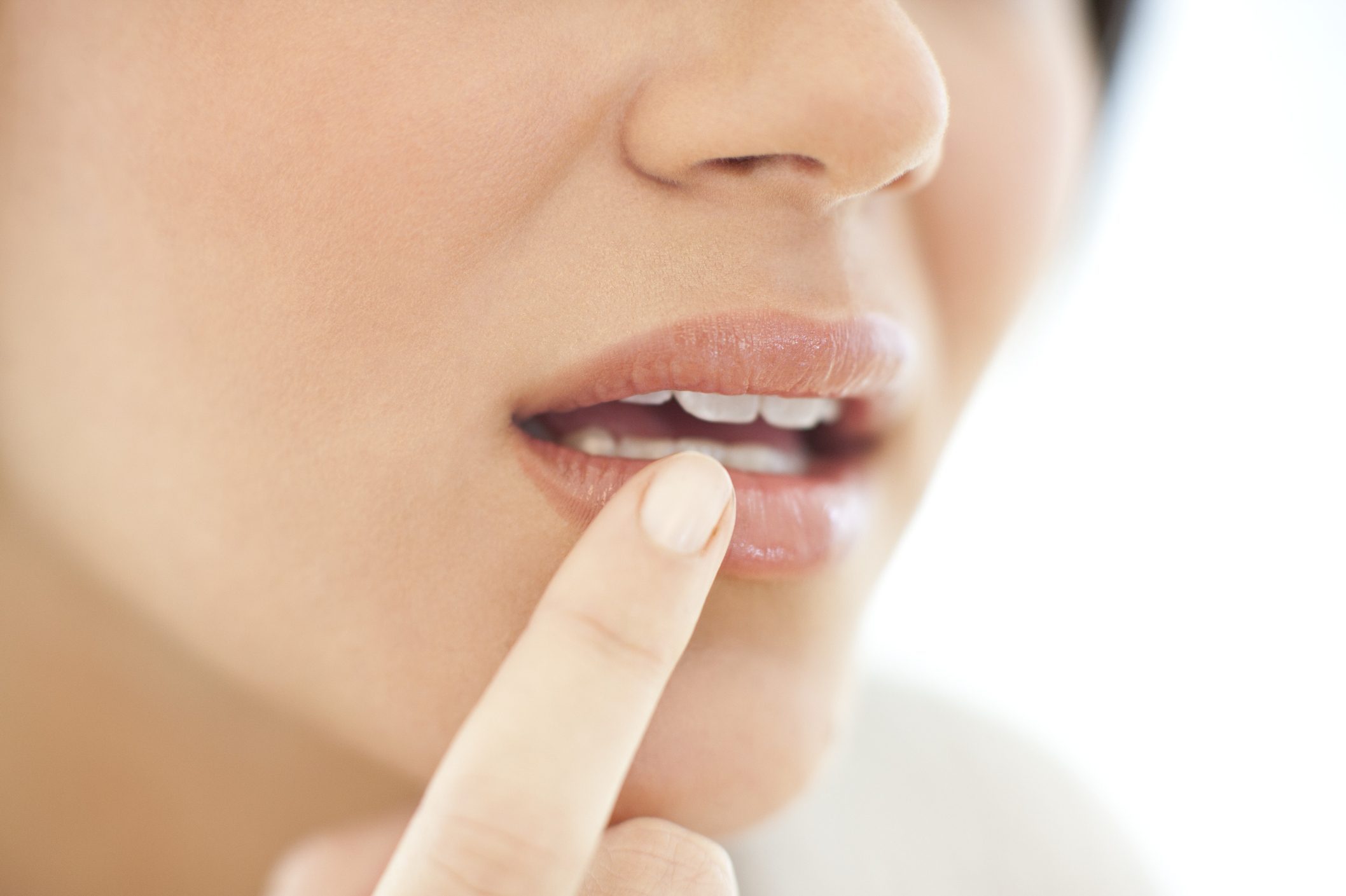 close up of woman with her finger on mouth area