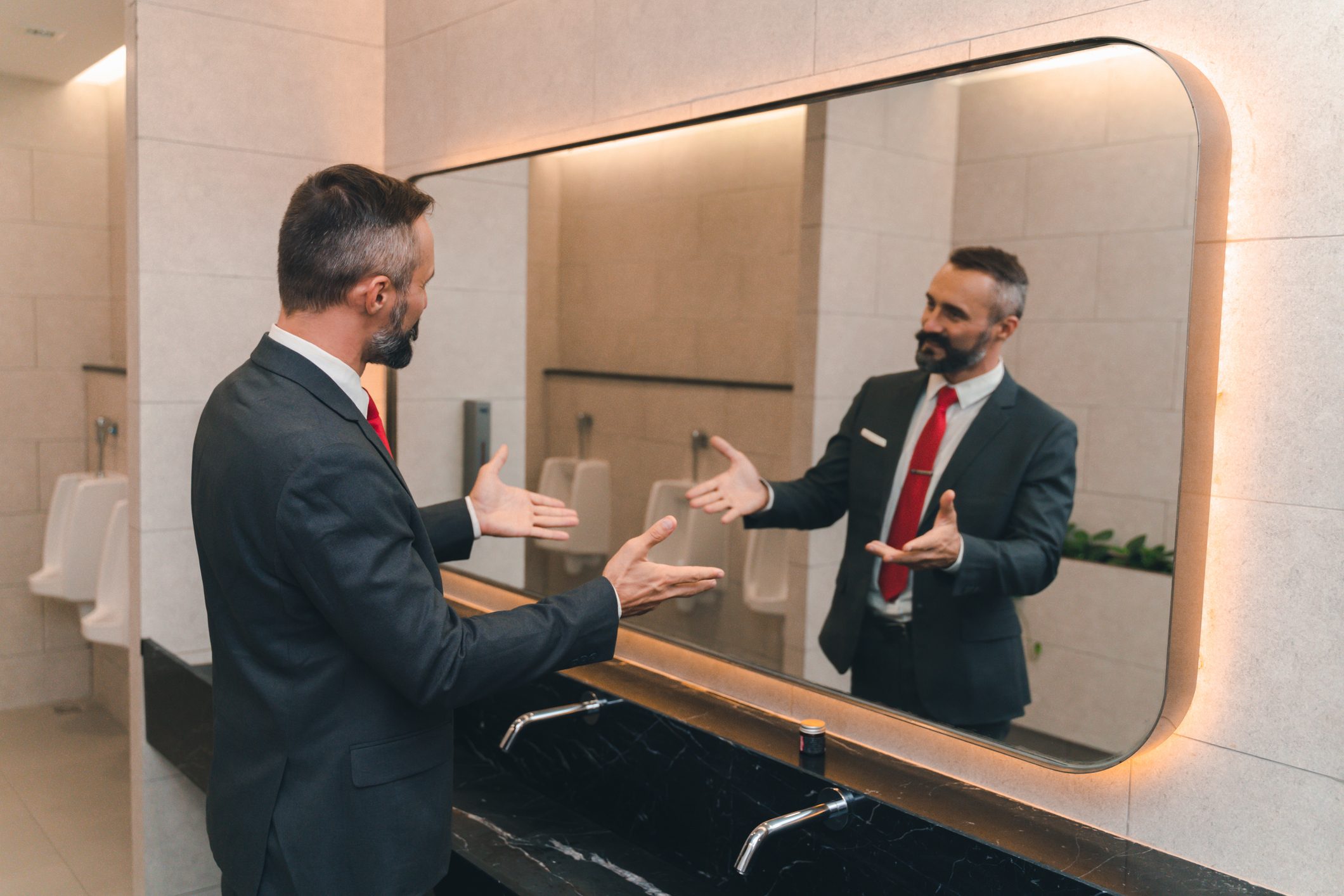 man business suit talking to himself in the bathroom mirror