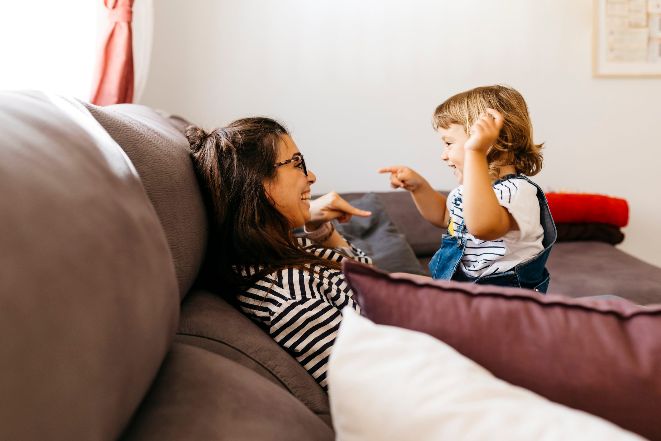 Happy mother and daughter talking while relaxing on sofa at home