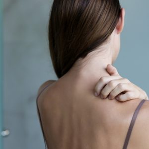 Close up view of woman scratching her neck.