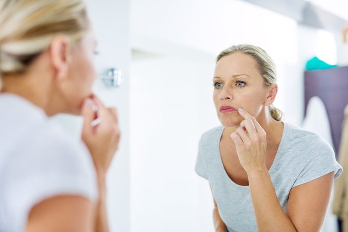 woman looking at her skin in the mirror