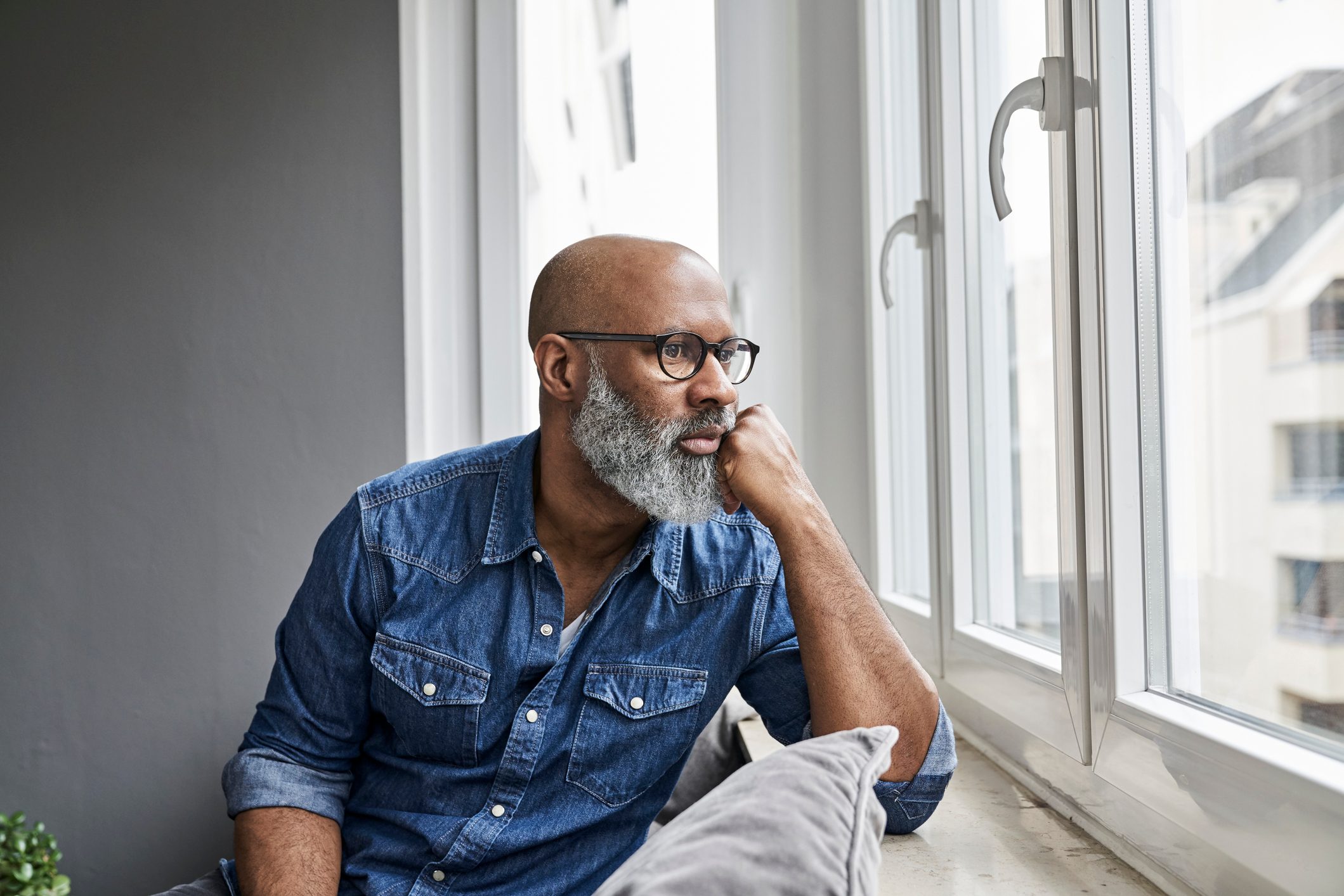 Mature man sitting at window, looking worried