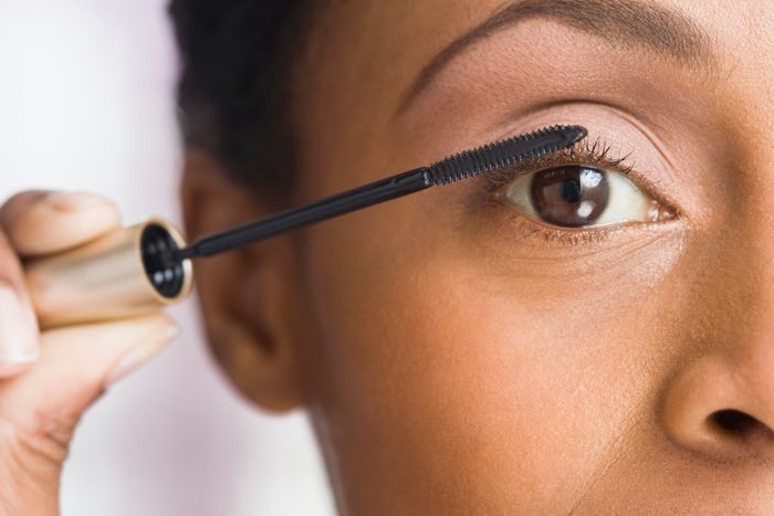 African American woman applying mascara