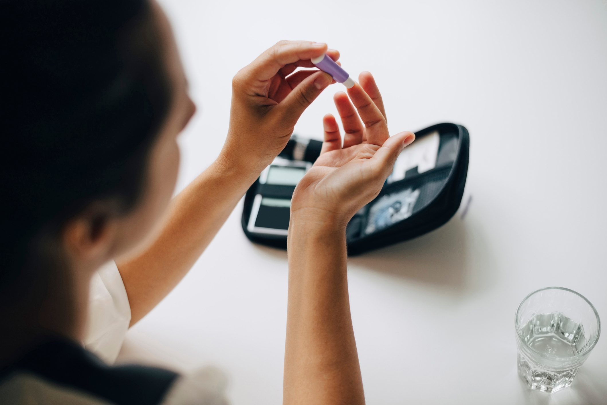 High angle view of businesswoman checking blood sugar at table