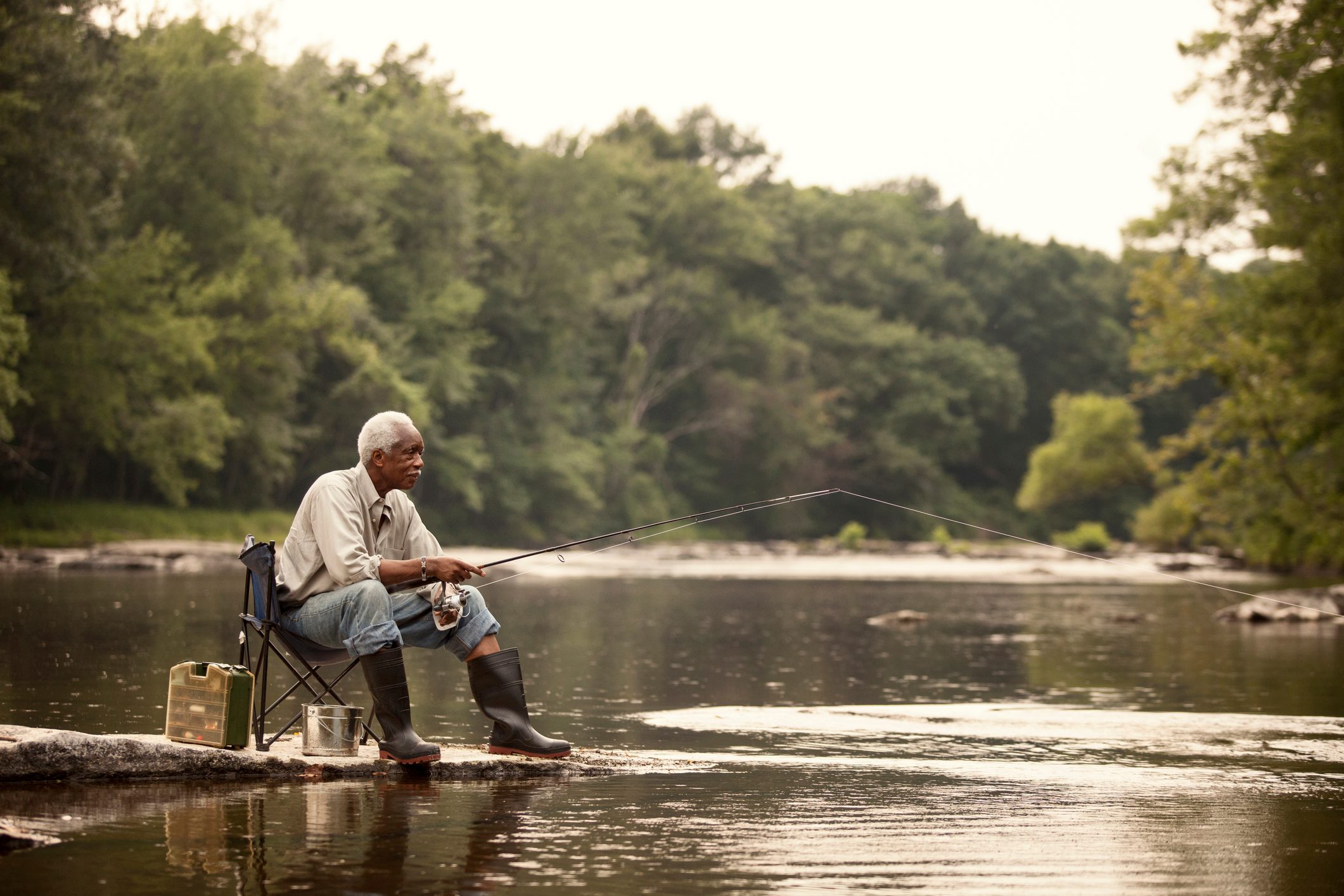 Man fishing while sitting on chair at lake