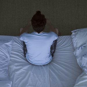 man sitting on edge of bed at night unable to sleep