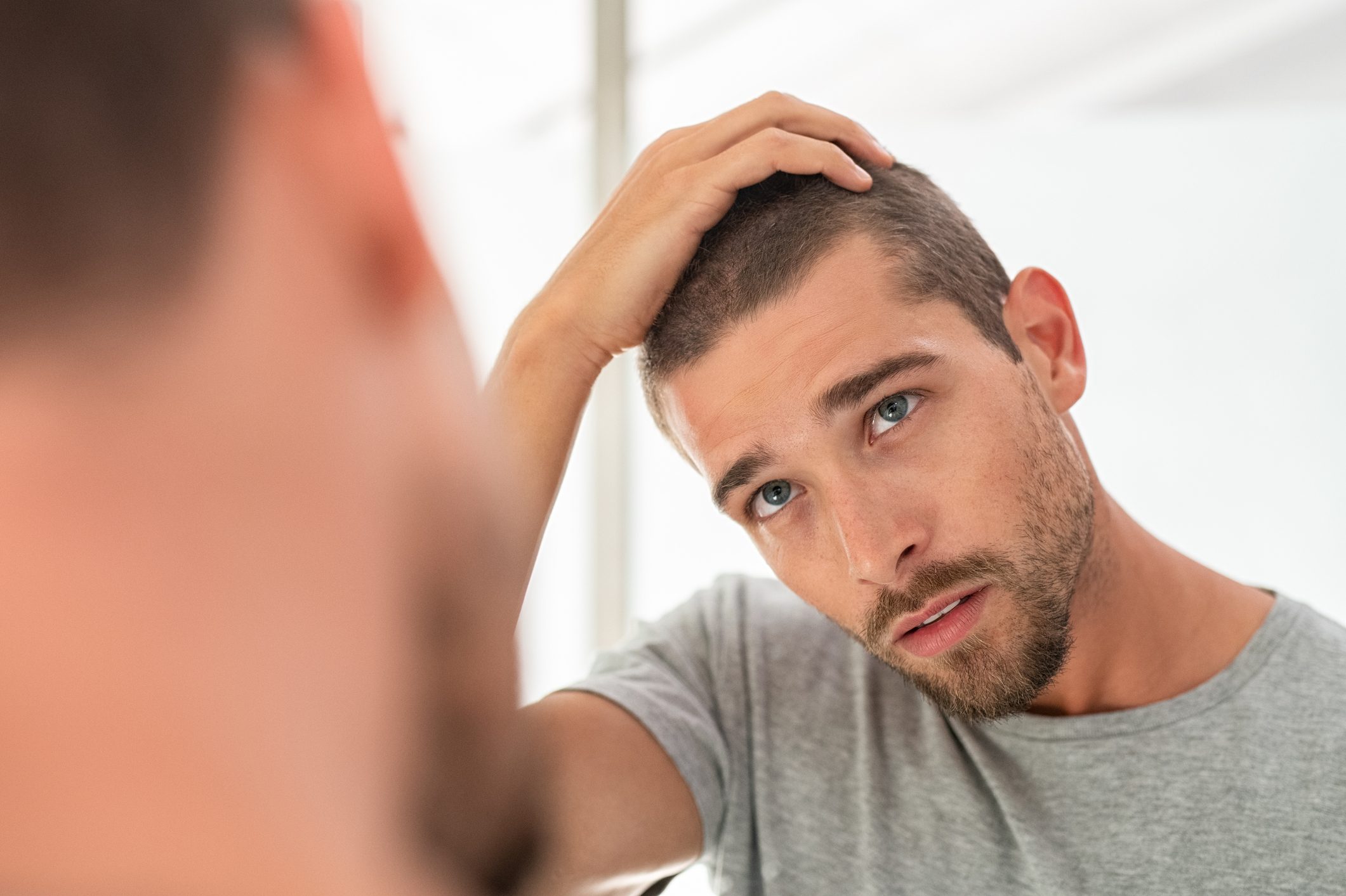 man checking hair in mirror