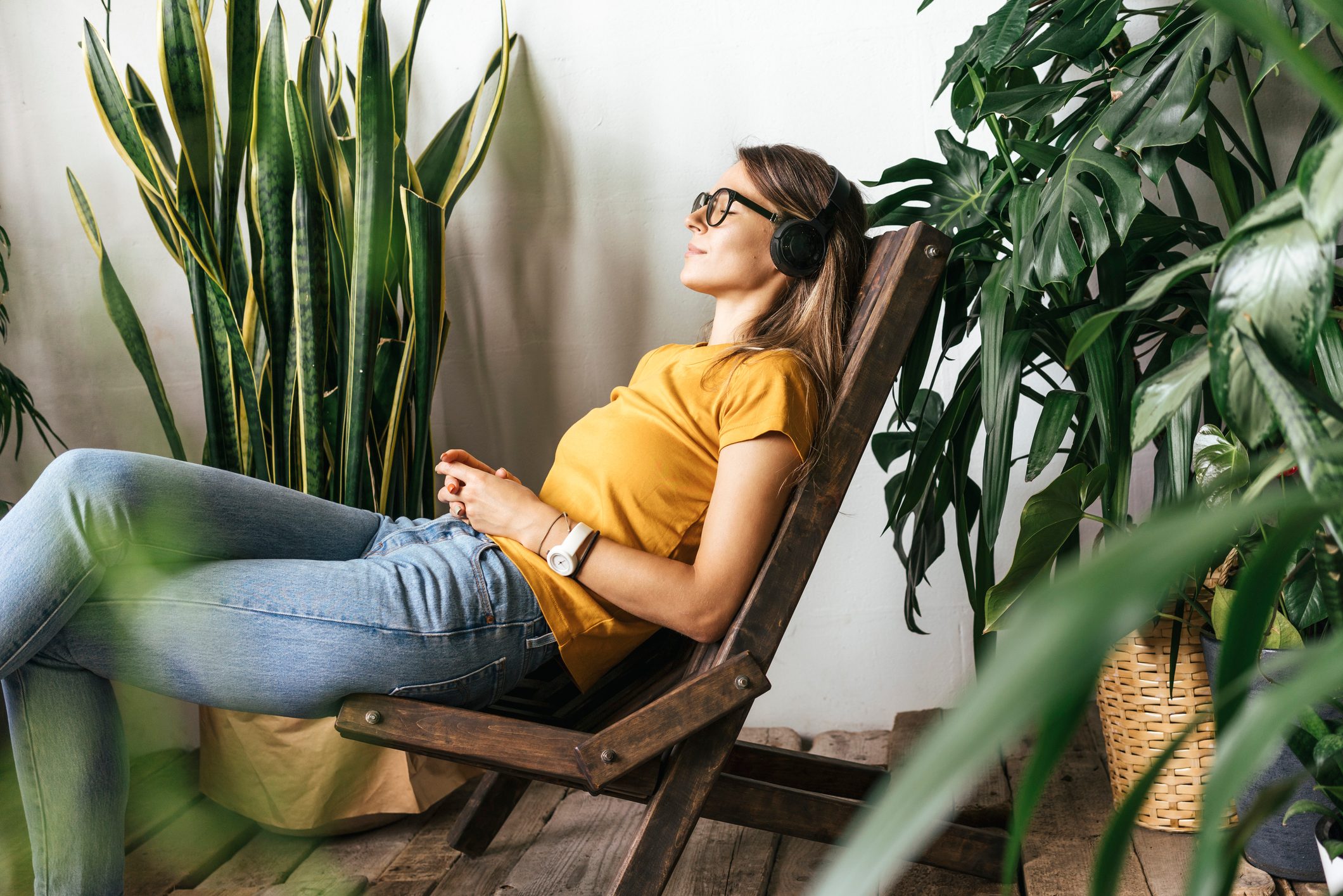 Relaxed young womansitting in chair listening to music at home