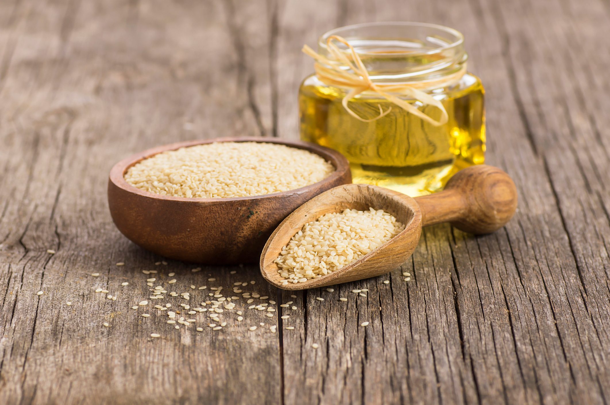 Glass bottle of sesame oil and raw sesame seeds