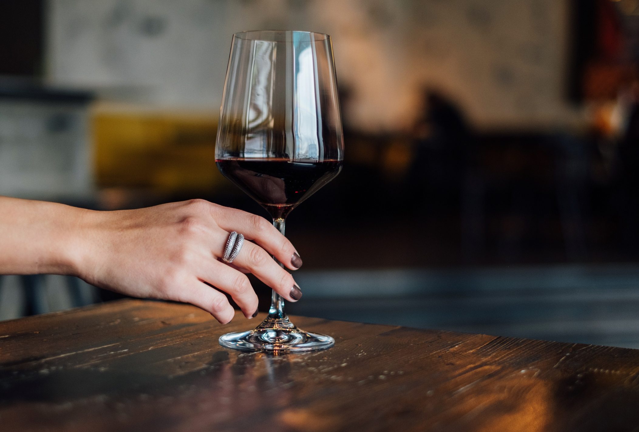 Close-Up Of Hand Holding wine glass On Table