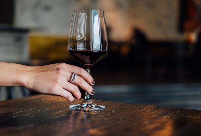 Close-Up Of Hand Holding wine glass On Table