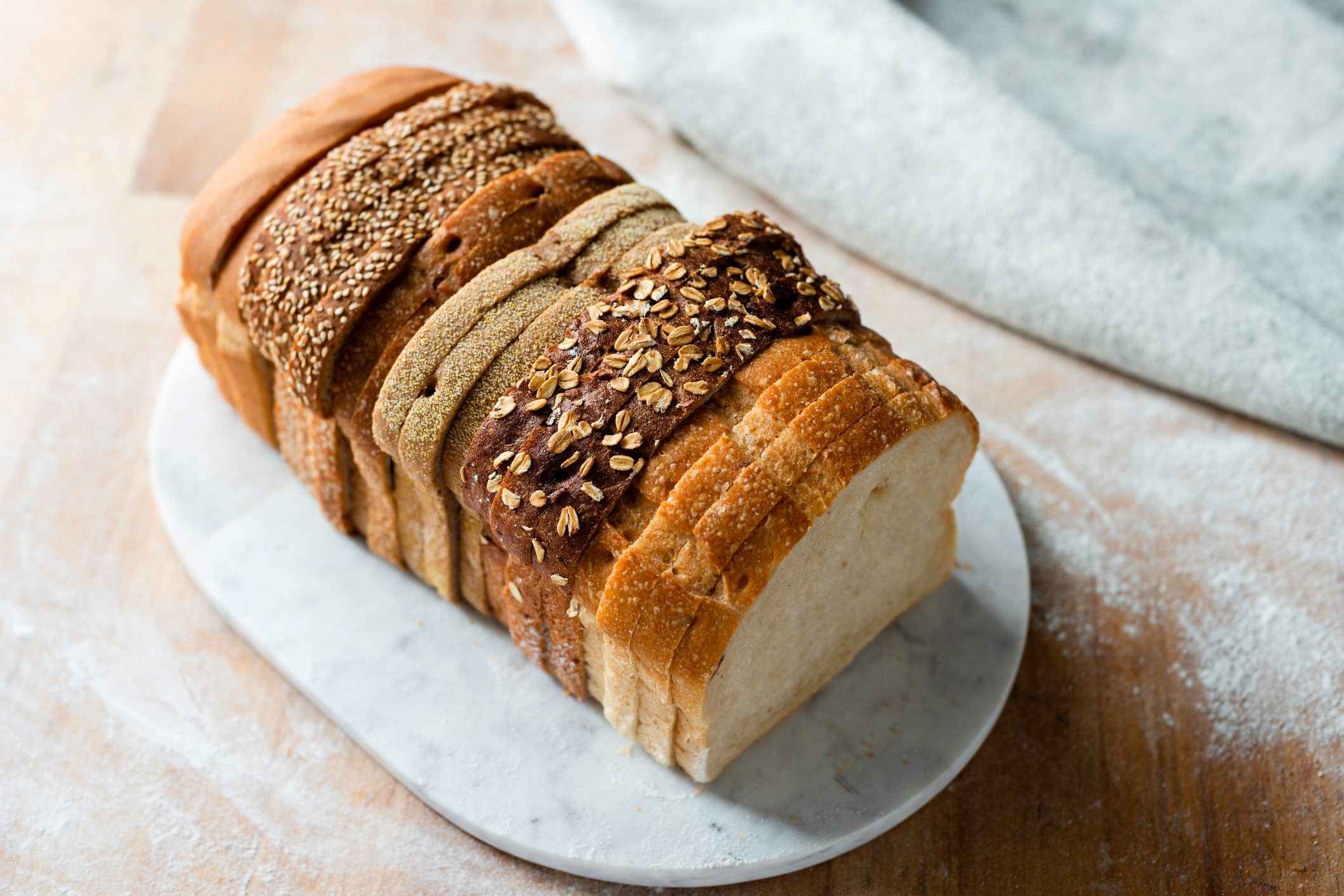 Sliced loaf made up of variety of white and wholemeal slices on cutting board, high angle view