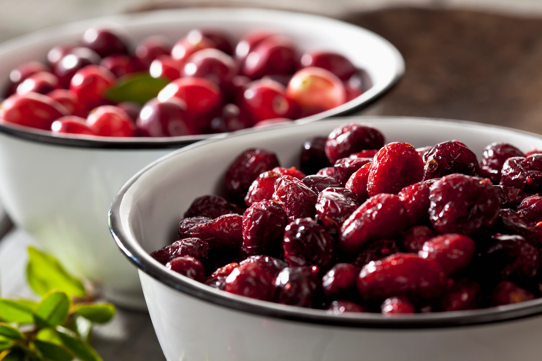 Two bowls of dried and fresh cranberries (Vaccinium macrocarpon), close-up