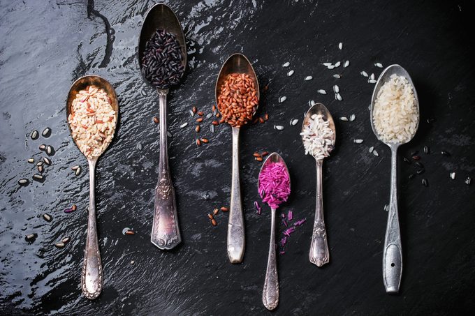 Directly Above Shot Of Various Rice In Spoons On Wet Slate