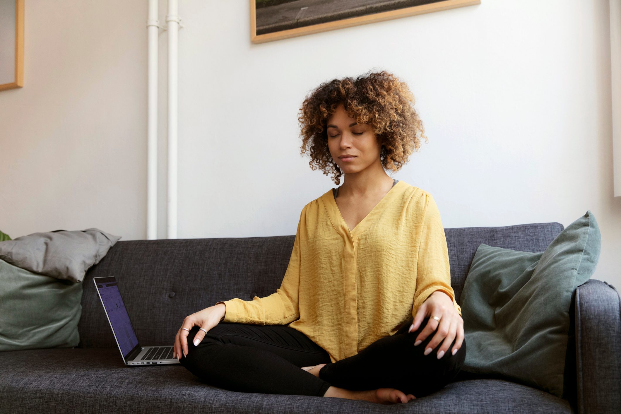 young woman sitting on couch doing breathing exercises