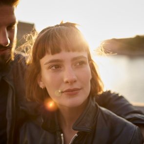 Young couple in backlight by the riverside