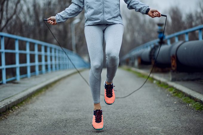 woman jumping rope on a bridge.