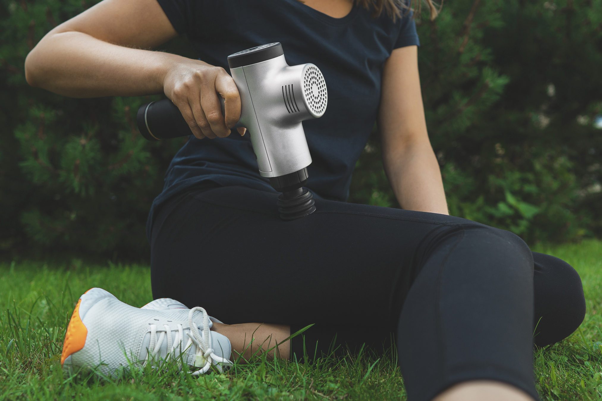 Woman massaging leg with massage percussion device