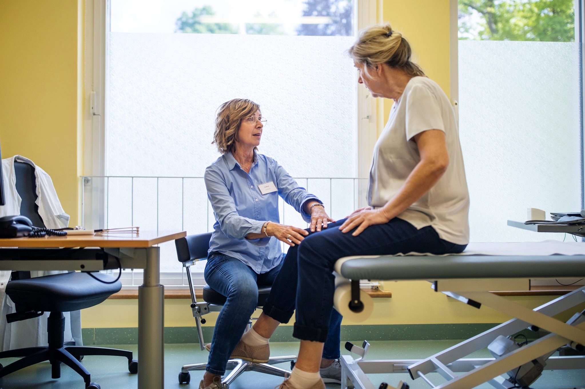 Physiotherapist checking knee of female patient stock