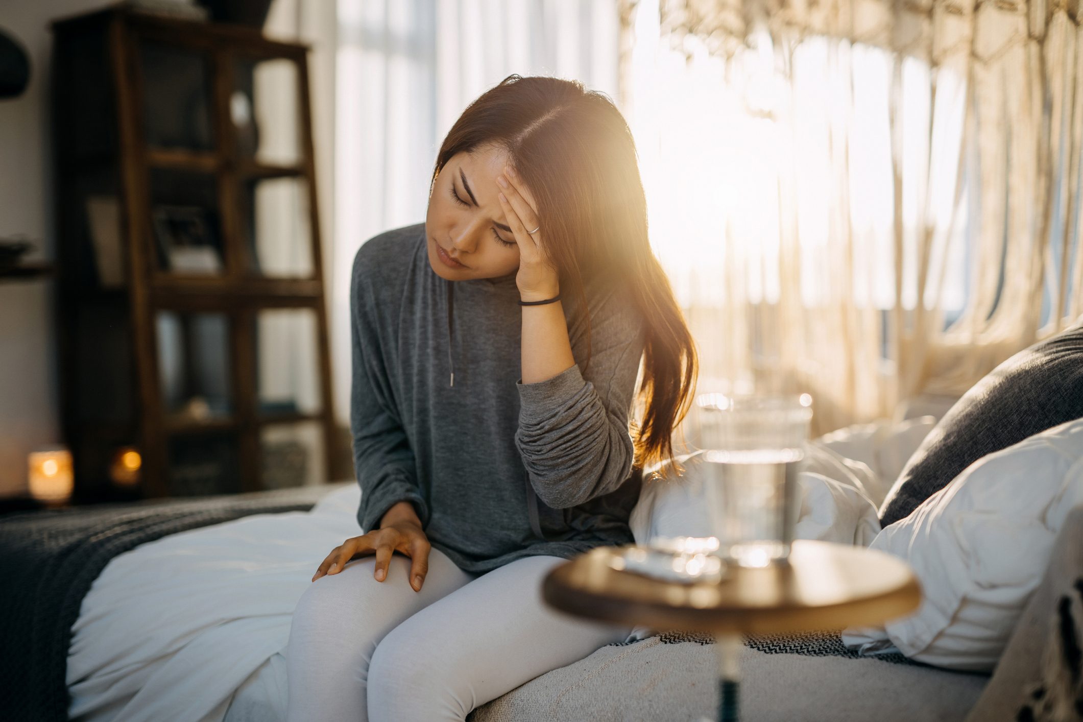 woman sitting in bed, holding her head