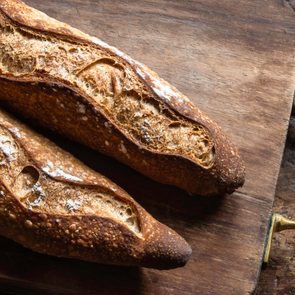 Two baguettes over a wood board on an old piece of wood. Still life.