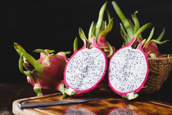 Close-Up Of Wet Pitayas On Wooden Table Against Black Background
