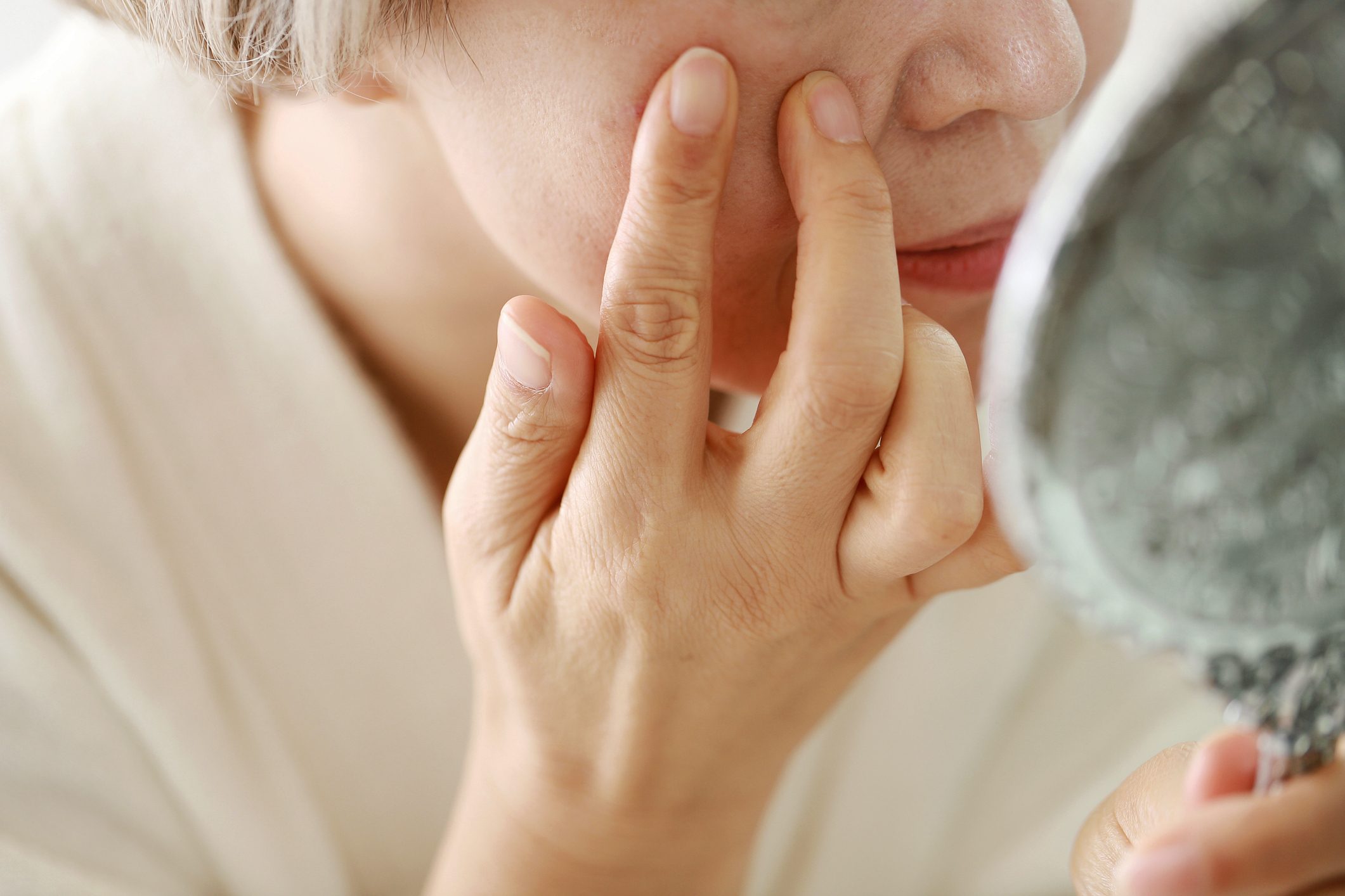 close up of woman looking at face in mirror