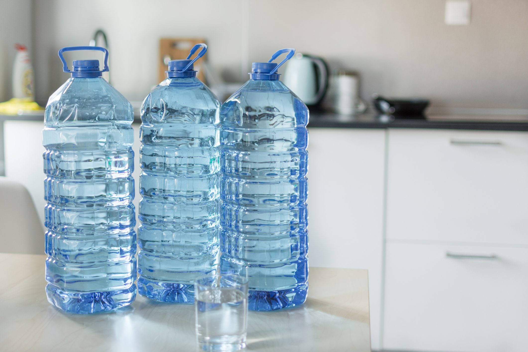 Big plastic bottle with water on the table over bright kitchen backgroung.