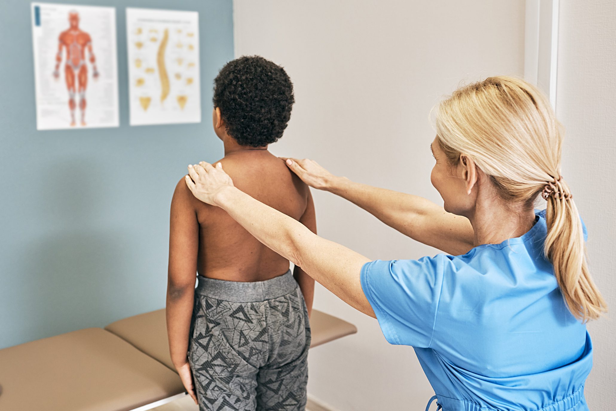 Osteopath examining spine to a male kid. Medical exam, scoliosis, kyphosis to a children