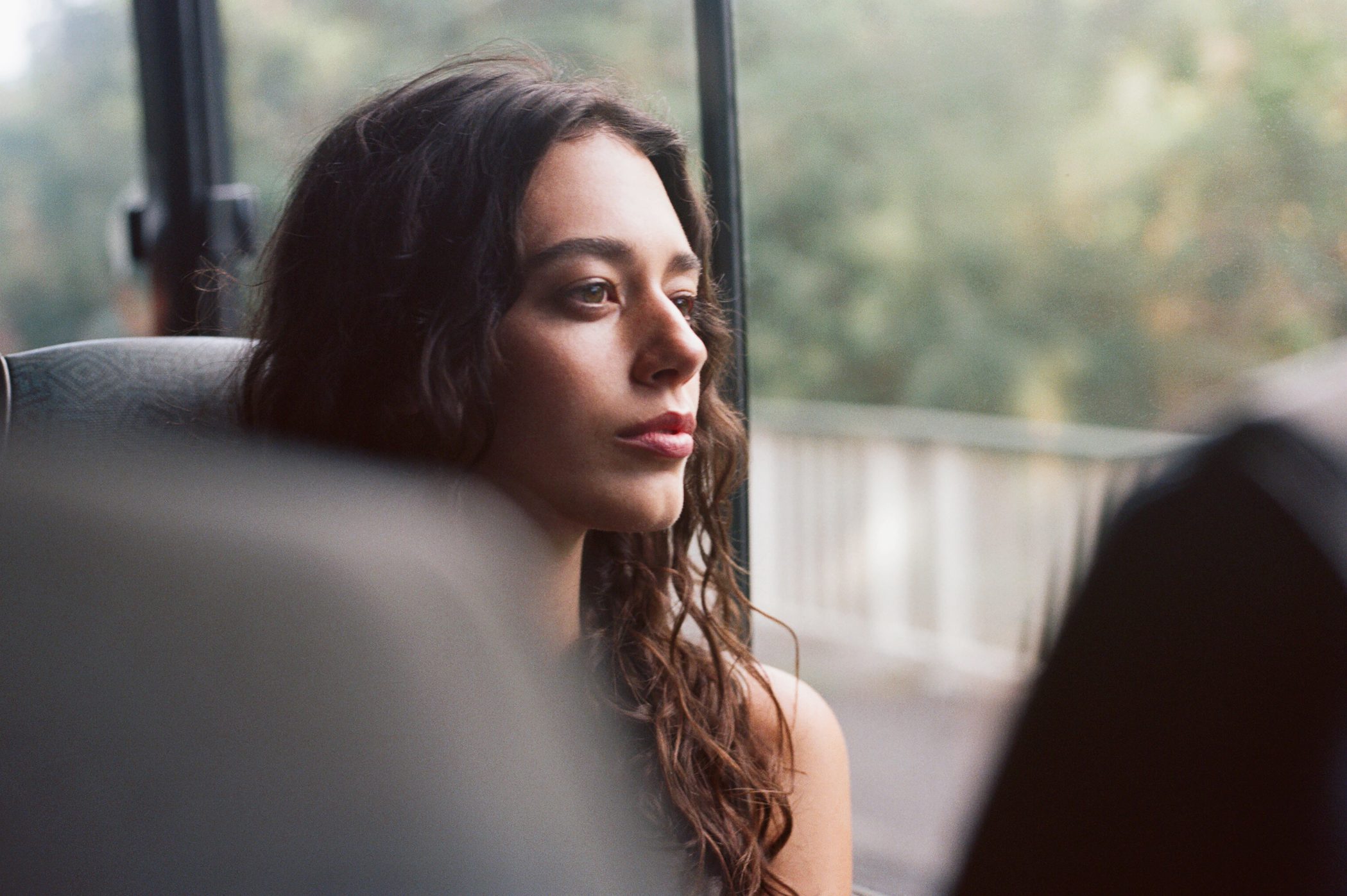 A young woman rides a bus and stares serenely out the window
