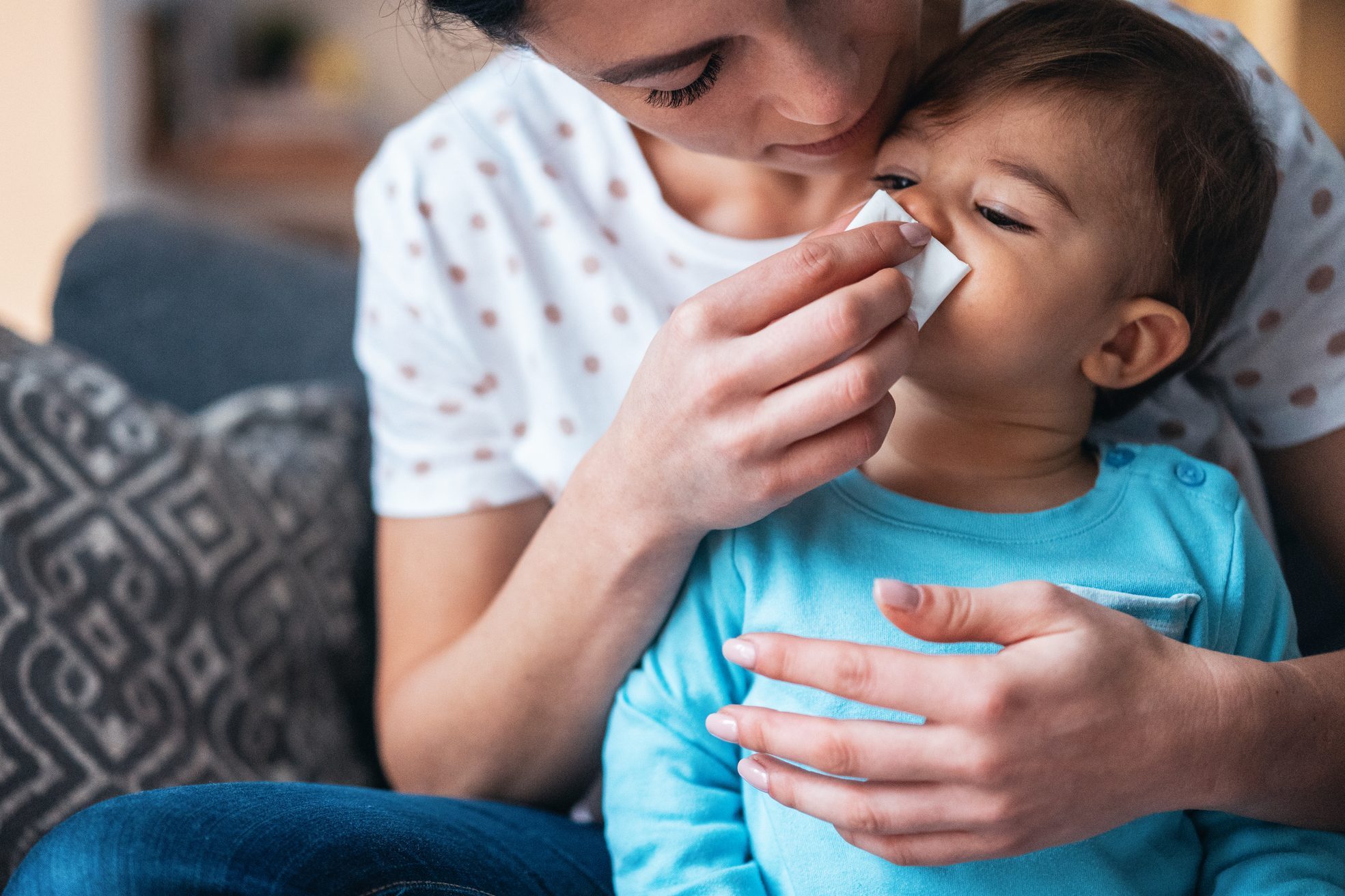 Mother helping her baby son to blow his nose