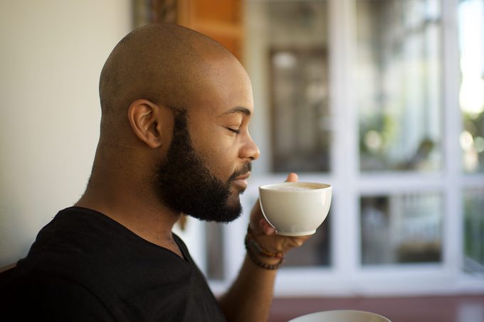 Millennial man smelling coffee in a cup