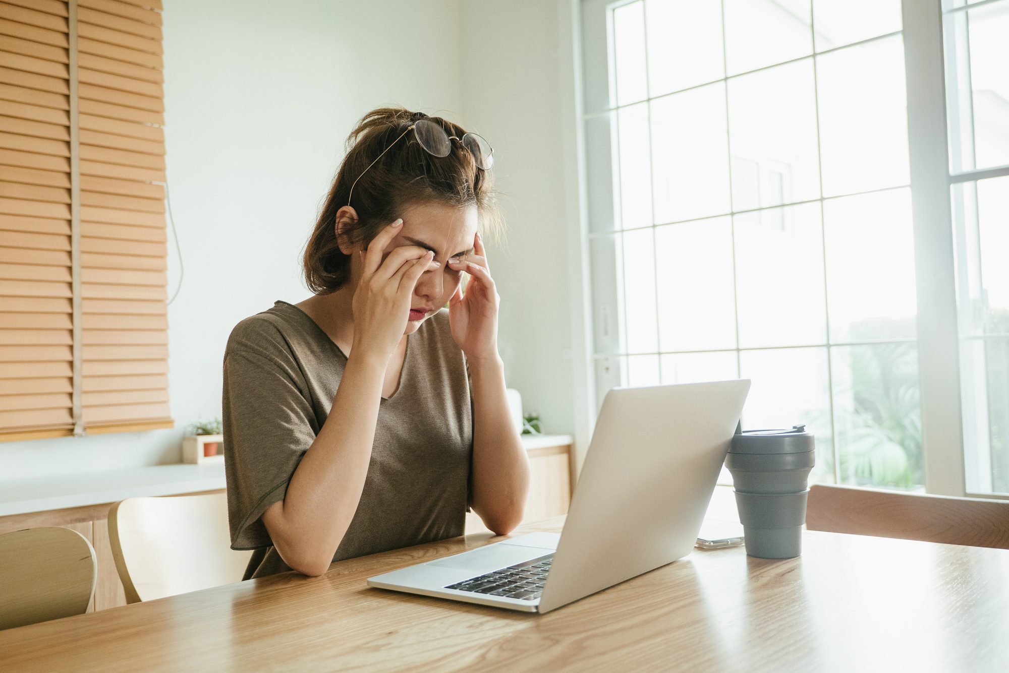 woman struggling with using laptop at home.