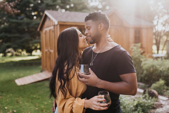 Couple holding wineglass while doing romance standing at backyard