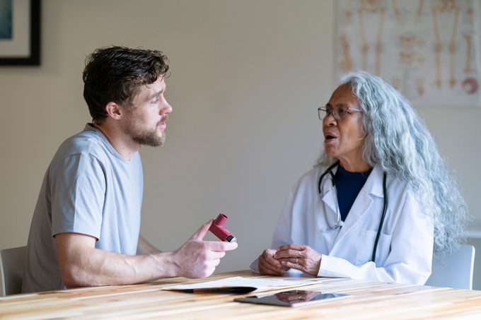Man in medical consultation discusses with his doctor using a puffer inhaler for asthma