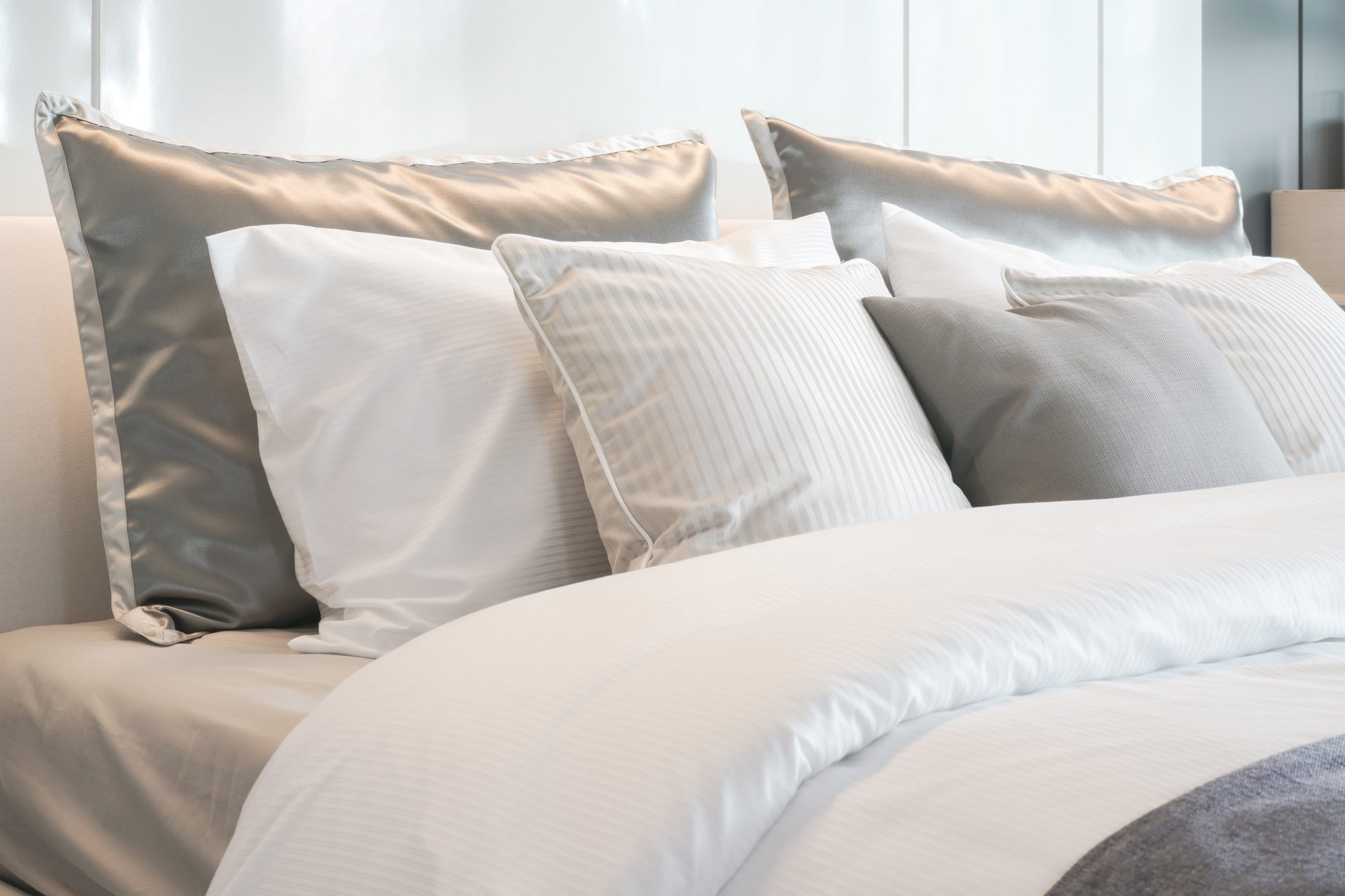 Gray color scheme pillows setting on bed with satin finished style bedding