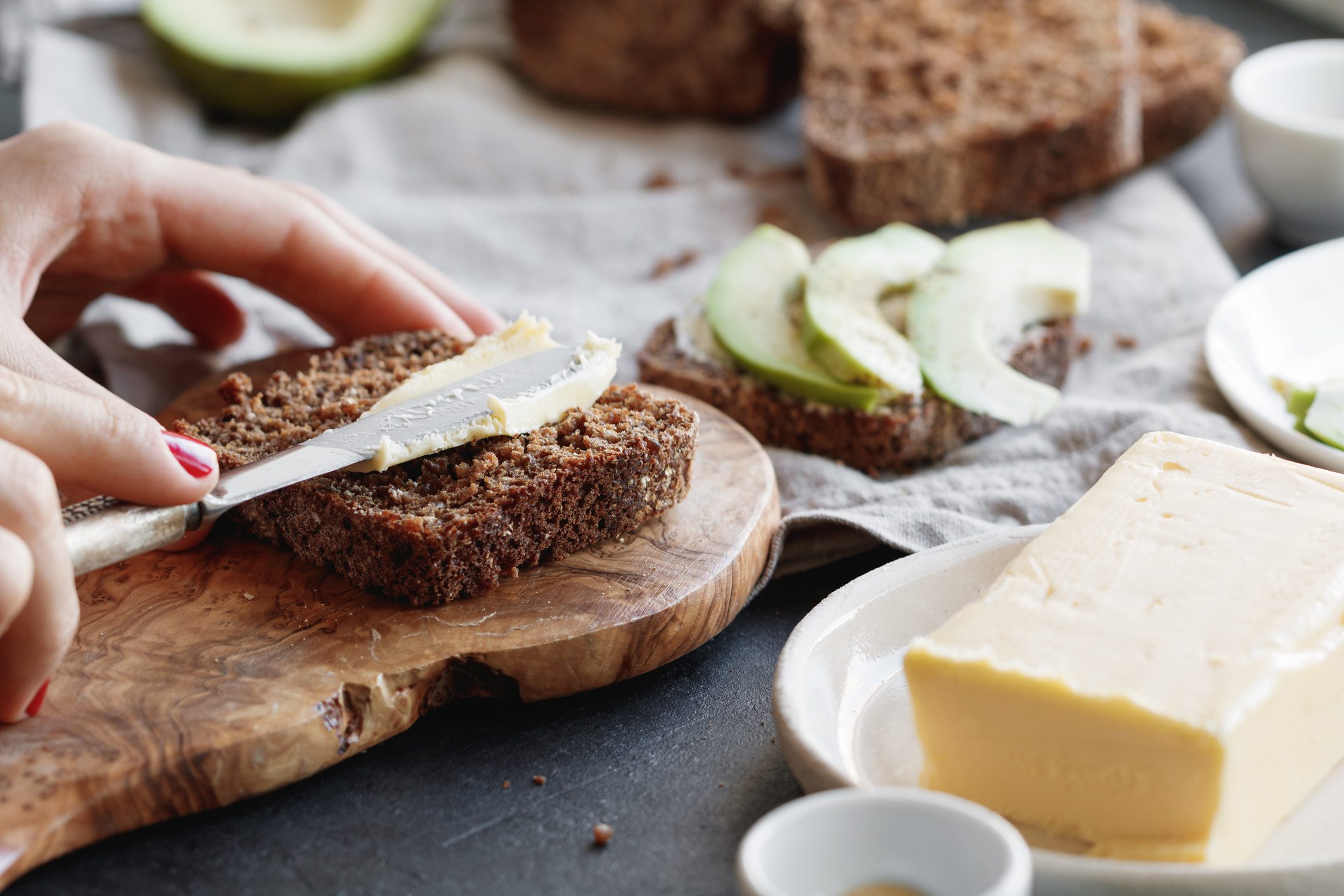 close up of unrecognizable person spreading butter on rye toast for breakfast